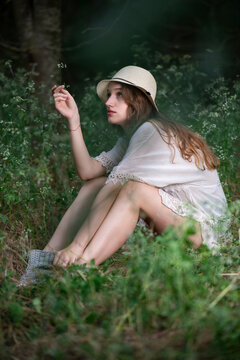 Beautiful young girl with a straw hat posing in a dark forest
