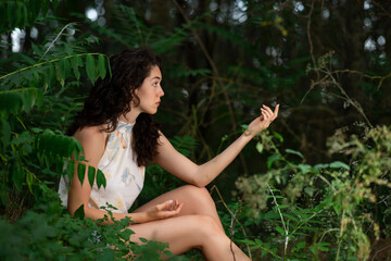 Beautiful young girl with curly hair posing in a dark forest
