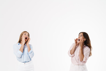 Image of excited caucasian two women screaming and looking upward