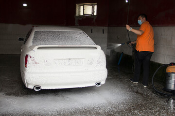
A man washes a car with foam