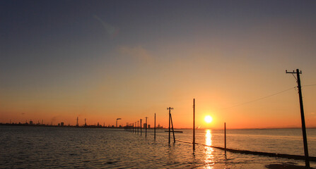海の上に建つ電柱と夕焼け