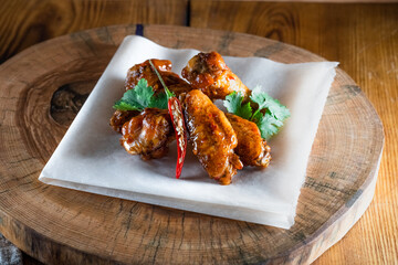 Appetizing fried chicken wings in sauce on a wooden tray. The concept of food and serving, food in bars and restaurants