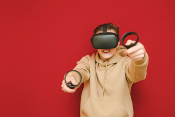 Crazy man in VR helmet plays video on controllers against red background, looks into the camera with a nervous face. Mad guy playing virtual reality games using a Vr helmet.