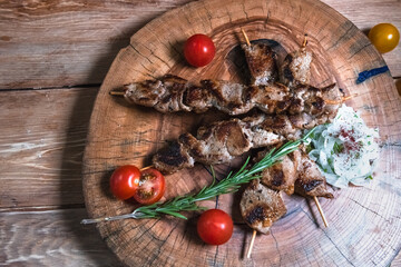 Appetizing pieces of meat on skewers on a wooden background. Food and serving concept
