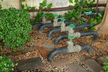Part of five water pipes with control valves run above ground of underground pipe system, selective...