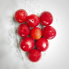 Colorful Red plums kept in bowl placed in white and black background and reduce the risk of cancer heart disease and diabetes