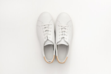 White women's sneakers on a light background, close-up, minimal, art, contemporary. Fashionable summer leather shoesю Flat lay, top view