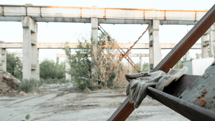 Dirty textile work gloves on metal stairs. Industrial zone, urban landscape with blurred background.