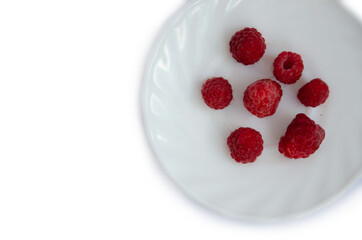 Red fresh raspberries on a white plate on a white background. Red summer berries on a white background
