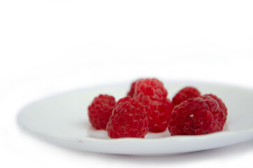 Red fresh raspberries on a white plate on a white background. Red summer berries on a white background
