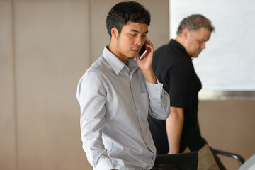 Multi ethnic business people using phone while having meeting at the office