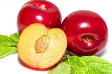 Plum fruits with green leaves and slice isolated on white