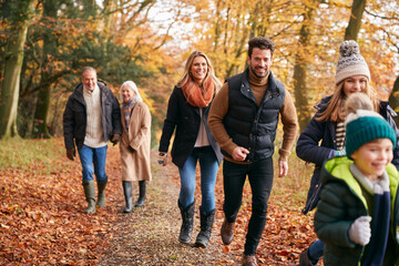 Multi-Generation Family Enjoying Walk Along Autumn Woodland Path Together