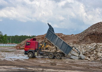 Dump truck unloading old concrete and asphalt from demolition for recycling. Landfill for disposal of construction waste. Gravel and concrete crushing. Salvaging, removal building materials © MaxSafaniuk