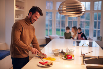 Man In Kitchen At Home Preparing Ingredients For Family Meal