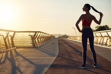 Beautiful girl working out and posing at sunrise. Young woman back view. Sport at the city. Wellness lifestyle in the city concept. Jogging in the morning