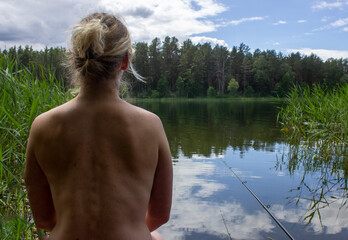 Naked woman from back fishing in lake