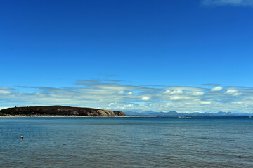 The waterfront at the beautiful Welsh seaside resort of Abersoch.  View over the Irish sea to the horizon and the cliffs of the bay.  Blue skies, copy space.
