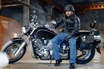 Fototapeta na wymiar Biker man in leather jacket and helmet sitting on his motorcycle