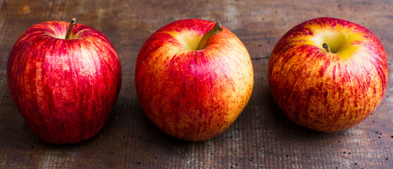 Three beautiful apples on an old wooden table. Panoramic picture.