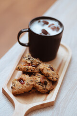Cup of hot coffee and chocolate cookies for breakfast on wooden table