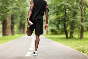 Cropped of black guy exercising at park, stretching legs