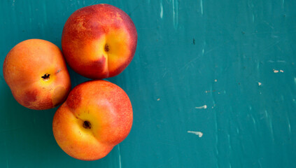 Three ripe peaches on a turquoise painted table