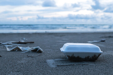 Rubbish (foam boxes) discarded on the beach.The background is sea 