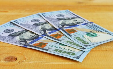 Currency of one hundred dollar bills on a natural wooden surface close up