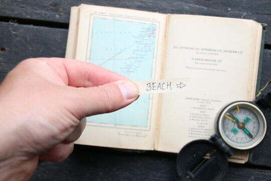 A pointer to the beach against the backdrop of a tourist atlas. 