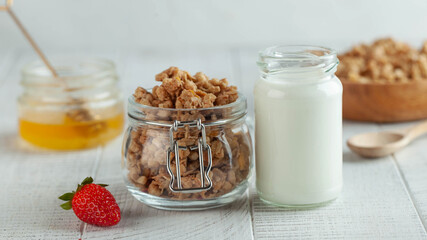 Banner with homemade granola, milk in a jar, honey and strawberries on a wooden background. The concept of a Breakfast.