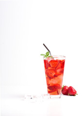 Refreshing strawberry lemonade with strawberries, lemon, mint, soda and ice in a glass stands on a white wooden table. Vertical orientation, there is a copy space.