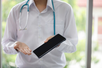 Asian male doctor is showing to a blank tablet screen for the patient to see. tablet mockup. modern hospital.