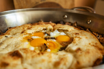 Fresh breakfast fried eggs in pita bread, in a large frying pan, closeup, shallow depth of field, selective focus. Fast breakfast concept