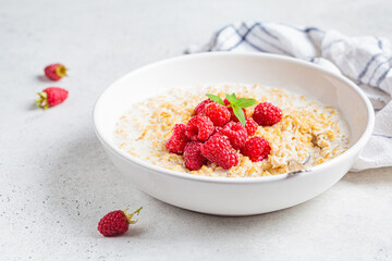 Breakfast oatmeal with raspberries in a white bowl. Healthy breakfast concept.