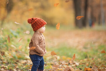 cute baby in autumn clothes looks to the right. child in knitted hats and jacket in cool weather....