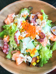 Vegetable salad seafood mixed with raw sliced salmon, octopus, caviar, green lettuce in a bowl, Japanese food