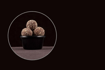 Healthy homemade sweets on black background. Fitness snack. Energy balls made of dates, apricots, almonds, pine nuts and prunes, with honey