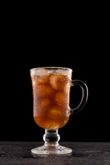 Iced coffee in a tall glass with a handle. Black background, close-up, copy space