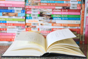 A close-up of a book opened on a library desk Stacks of books in the background selective focus and shallow depth of field