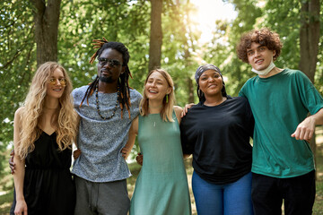 make love, not war, be tolerant. friendly group of mixed race people have fun outdoors, diverse men and women have rest, communicate and laugh in the park