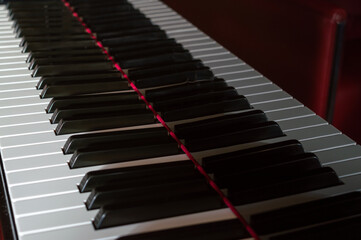 Closeup of the keyboard of a piano. Keys reflecting in the body of the piano
