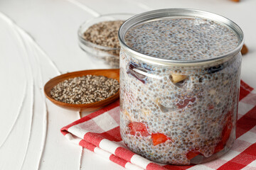 Chia pudding and raw chia seeds on white table