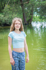 In the summer afternoon, a teenager girl stands in a lake.