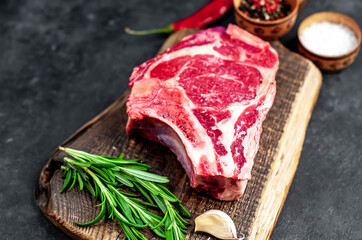 Raw cowboy steak. Marbled beef meat 
with spices on a stone background