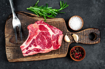 Obraz na płótnie Canvas Raw cowboy steak. Marbled beef meat with spices on a stone background