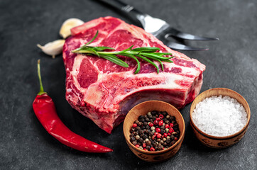 Raw cowboy steak. Marbled beef meat 
with spices on a stone background
