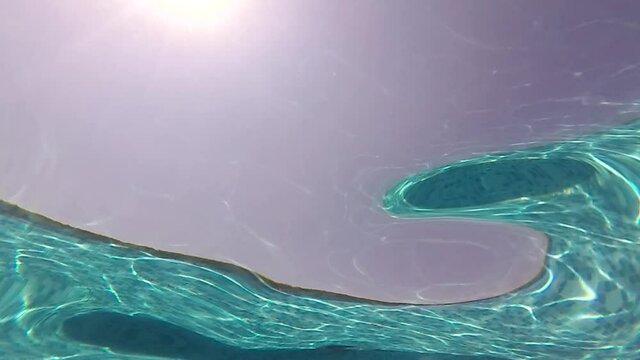 an abstract slow motion shot of pool and sun details from the water