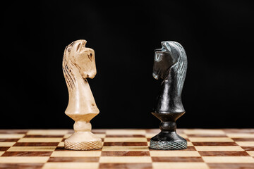 pieces of knights facing each other on a chessboard against a black background
