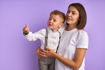 Look, I want it! adorable caucasian child boy shows to the side, careful mother hugs her son and attentively listen